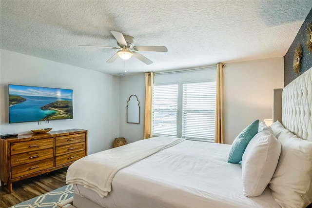 bedroom with ceiling fan, dark wood-type flooring, and a textured ceiling