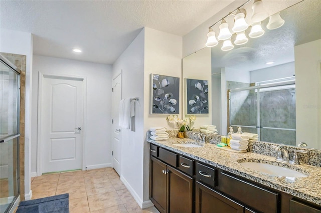 bathroom with vanity, a shower with shower door, tile patterned floors, and a textured ceiling