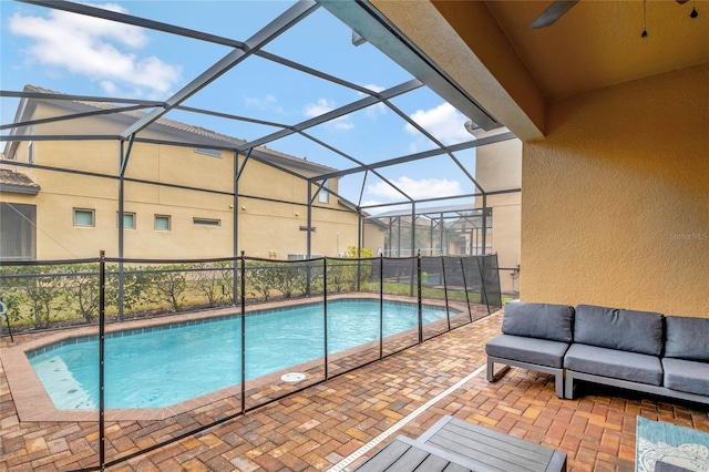 view of pool featuring a patio, outdoor lounge area, and glass enclosure