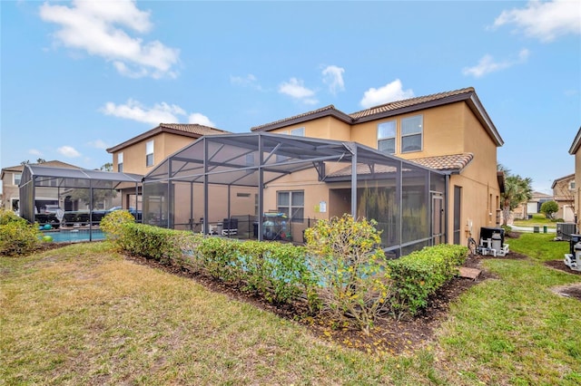 back of house with a lanai and a lawn