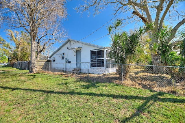 view of side of property with a sunroom, a fenced backyard, and a yard