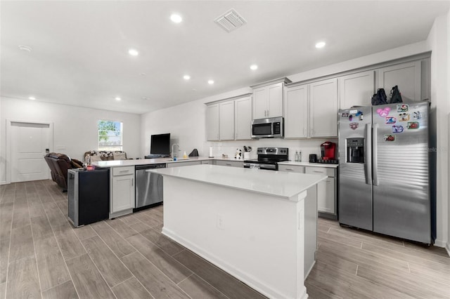 kitchen with a center island, gray cabinets, kitchen peninsula, and appliances with stainless steel finishes