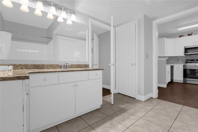 kitchen with stainless steel appliances, white cabinetry, light tile patterned floors, and decorative backsplash