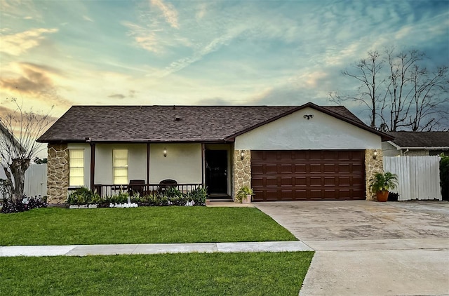 ranch-style house featuring a garage, a lawn, and covered porch