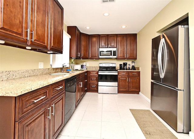 kitchen featuring appliances with stainless steel finishes, light stone countertops, sink, and light tile patterned floors