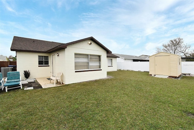 back of house featuring a storage shed, a patio area, and a lawn