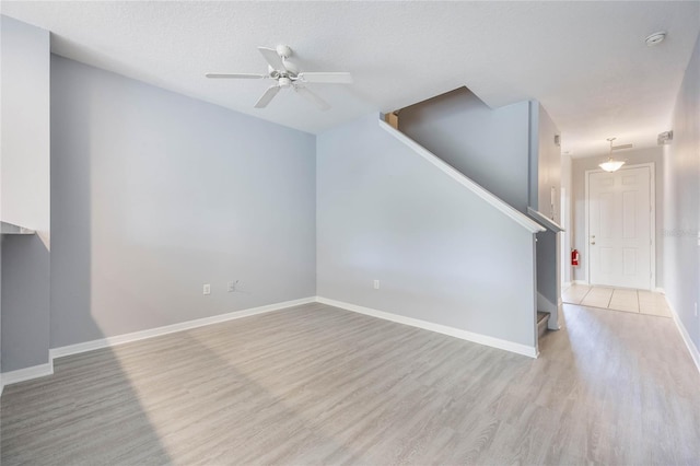 unfurnished living room with ceiling fan, light hardwood / wood-style flooring, and a textured ceiling