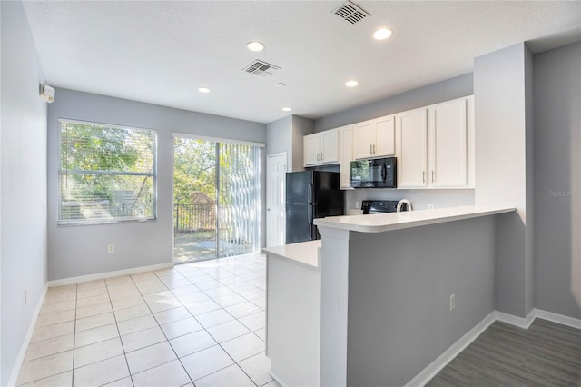 kitchen featuring black appliances, a textured ceiling, white cabinets, light tile patterned flooring, and kitchen peninsula