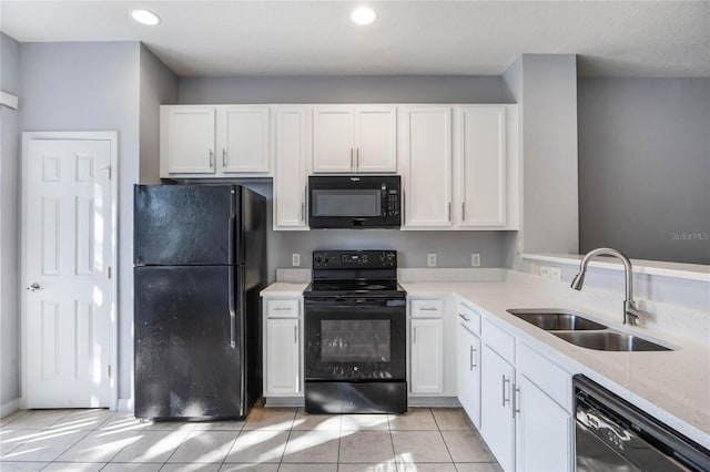 kitchen with light tile patterned flooring, white cabinetry, sink, black appliances, and light stone countertops