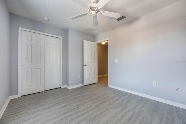 unfurnished bedroom with ceiling fan, a textured ceiling, light hardwood / wood-style floors, and a closet