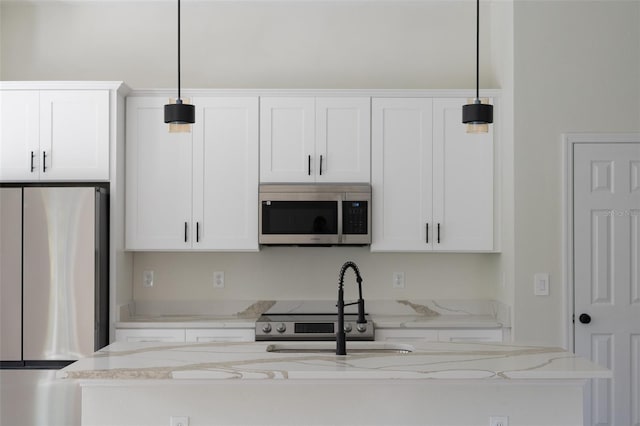 kitchen featuring light stone countertops, decorative light fixtures, stainless steel appliances, and white cabinets