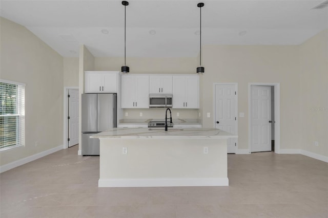 kitchen with a kitchen island with sink, white cabinetry, hanging light fixtures, stainless steel appliances, and light stone countertops