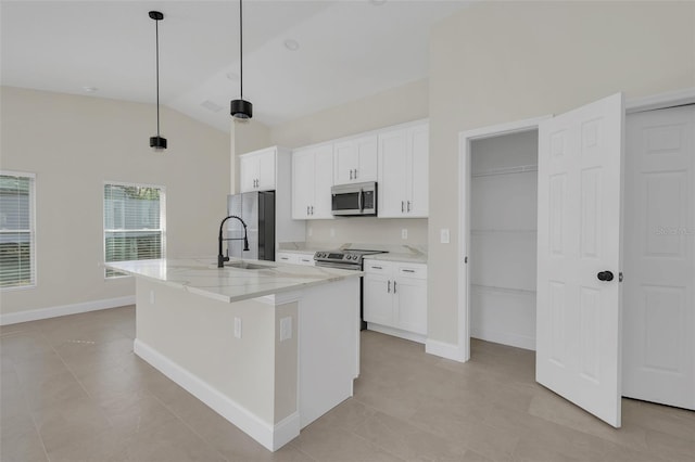 kitchen featuring appliances with stainless steel finishes, a kitchen island with sink, light stone countertops, white cabinets, and decorative light fixtures