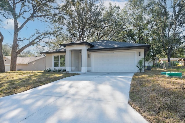 view of front of home with a garage, a front yard, and central AC unit