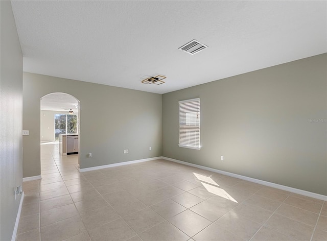 tiled empty room featuring a textured ceiling