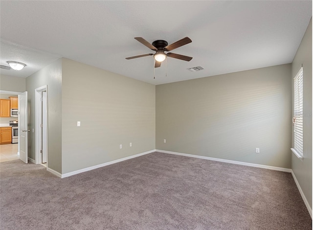 unfurnished room featuring ceiling fan, light colored carpet, and a textured ceiling