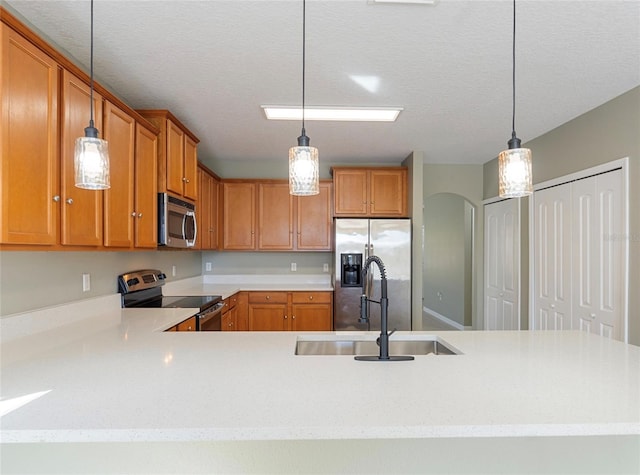 kitchen with sink, decorative light fixtures, stainless steel appliances, and a textured ceiling