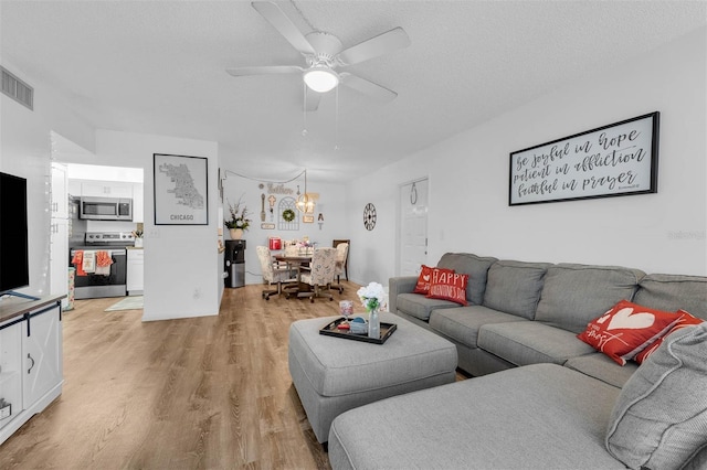 living room with ceiling fan, light hardwood / wood-style flooring, and a textured ceiling