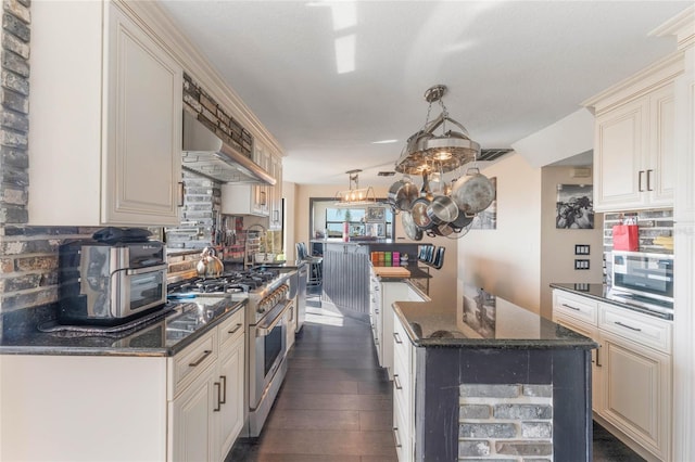 kitchen featuring dark stone countertops, dark hardwood / wood-style floors, wall chimney exhaust hood, and appliances with stainless steel finishes