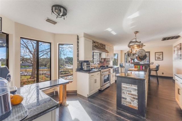 kitchen with pendant lighting, high end stainless steel range oven, dark hardwood / wood-style floors, a kitchen island, and custom exhaust hood