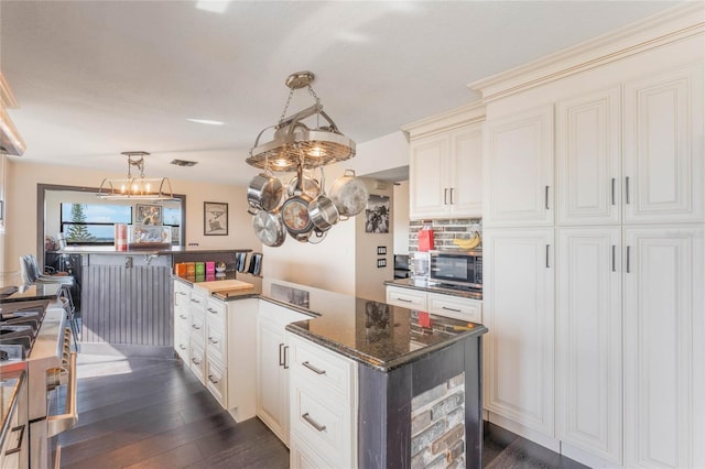 kitchen featuring hanging light fixtures, dark stone countertops, dark hardwood / wood-style floors, a notable chandelier, and backsplash