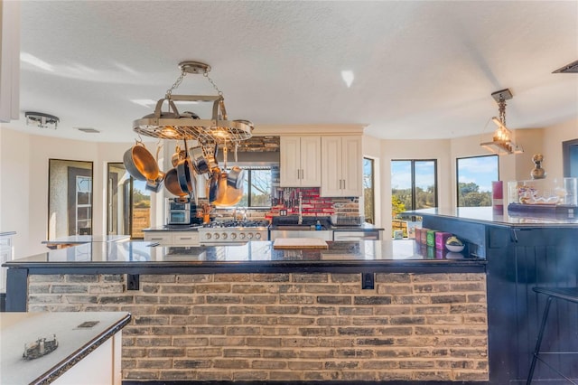 kitchen featuring sink, range, backsplash, a textured ceiling, and decorative light fixtures