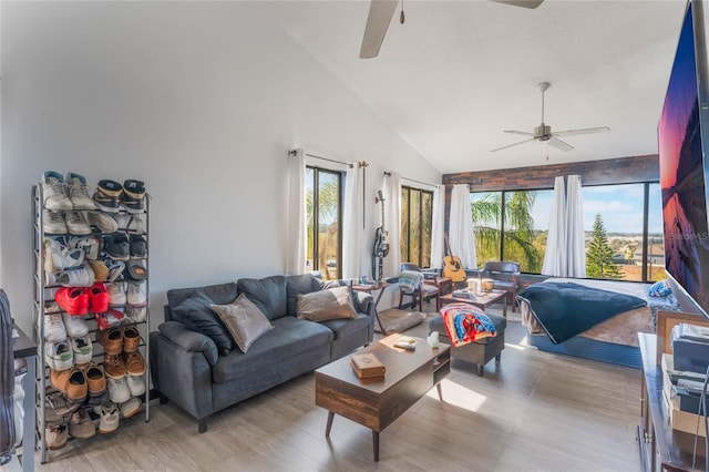 living room featuring ceiling fan, high vaulted ceiling, and light wood-type flooring