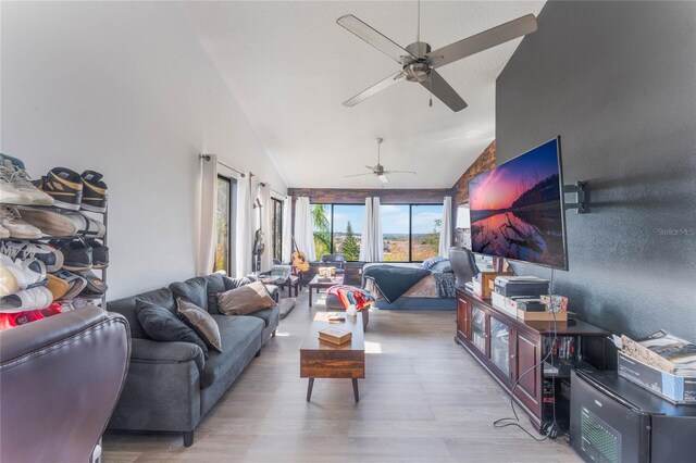 living room featuring ceiling fan, high vaulted ceiling, and light hardwood / wood-style floors