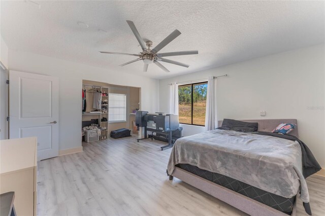 bedroom featuring ceiling fan, light hardwood / wood-style flooring, a closet, and a textured ceiling