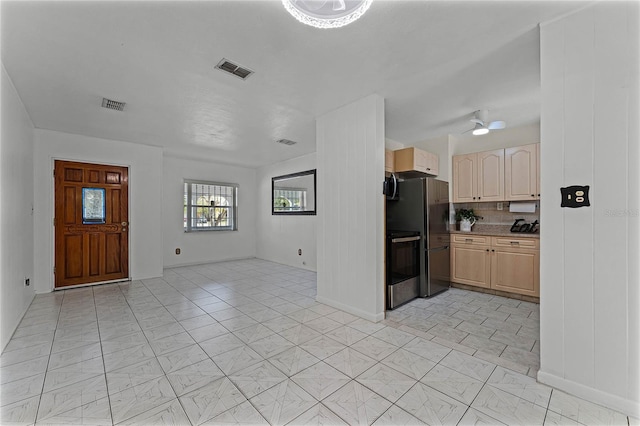 kitchen featuring black fridge, stove, light tile patterned floors, and light brown cabinets