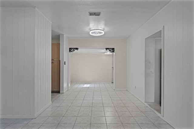 corridor featuring light tile patterned floors and wood walls