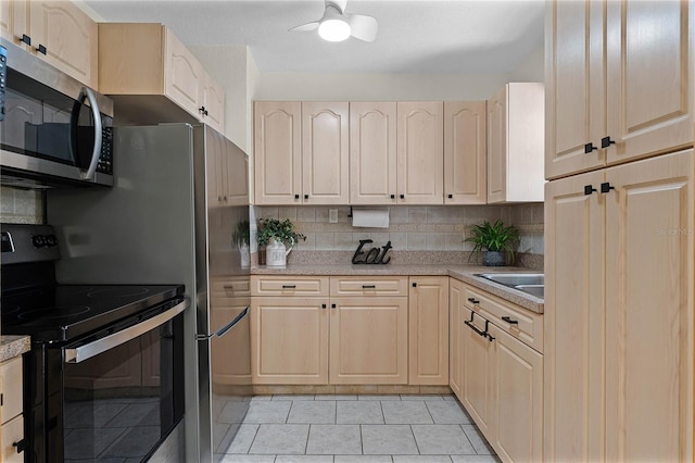 kitchen with light tile patterned flooring, light brown cabinetry, sink, backsplash, and electric stove