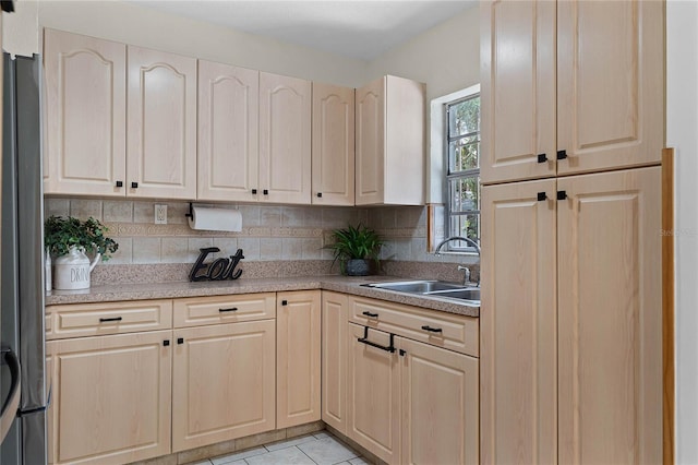 kitchen with sink, decorative backsplash, stainless steel refrigerator, and light tile patterned floors