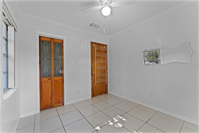 spare room featuring crown molding, light tile patterned floors, and ceiling fan