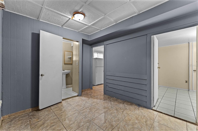 unfurnished room featuring tile patterned floors, sink, and wood walls