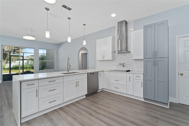 kitchen featuring hanging light fixtures, dishwasher, kitchen peninsula, and wall chimney exhaust hood