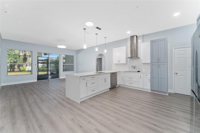 kitchen with pendant lighting, wall chimney range hood, dishwasher, white cabinetry, and kitchen peninsula