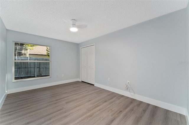 unfurnished room with ceiling fan, a textured ceiling, and light wood-type flooring