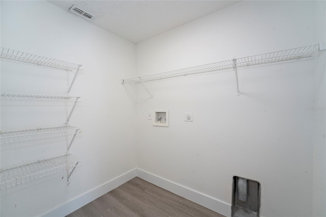 laundry room with electric dryer hookup, hardwood / wood-style floors, hookup for a washing machine, and a textured ceiling