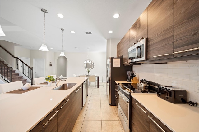 kitchen with pendant lighting, stainless steel appliances, sink, and light tile patterned floors