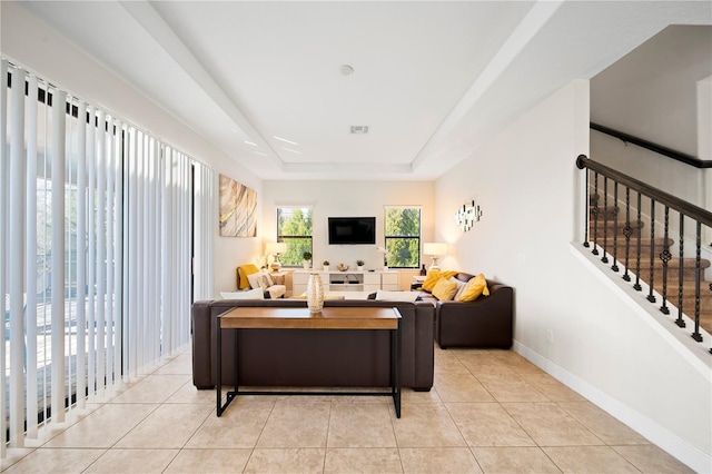 living room featuring a raised ceiling and light tile patterned floors