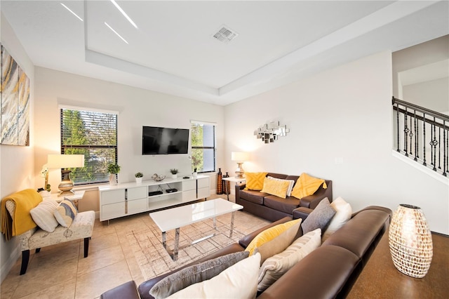 living room with a tray ceiling and light tile patterned floors