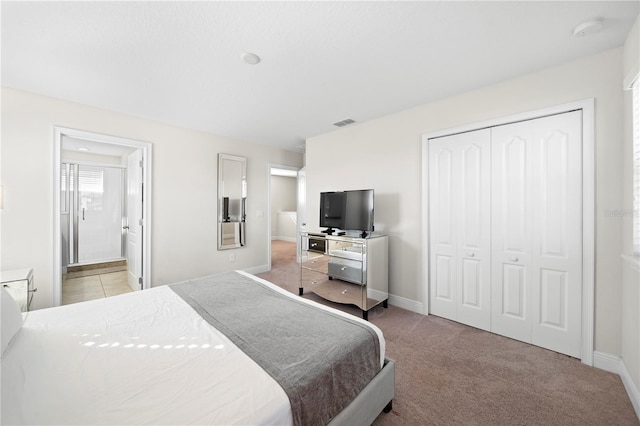 bedroom with connected bathroom, light colored carpet, and a closet