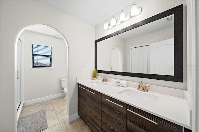 bathroom featuring tile patterned flooring, vanity, an enclosed shower, and toilet