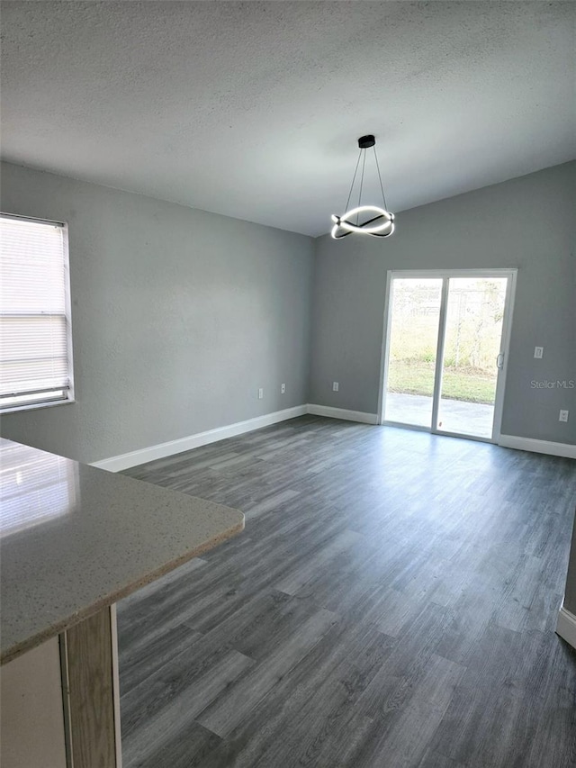 unfurnished dining area with dark hardwood / wood-style floors, a textured ceiling, and an inviting chandelier