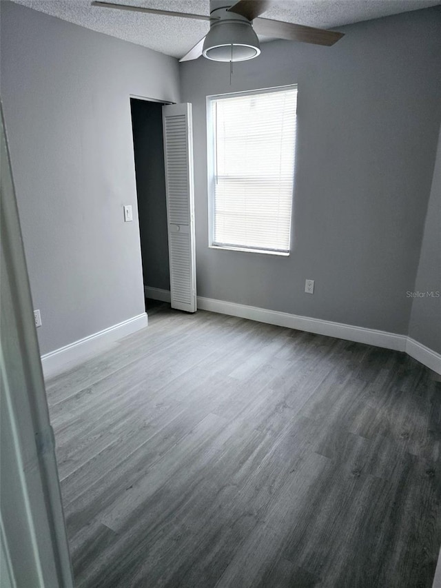 unfurnished room featuring ceiling fan, wood-type flooring, and a textured ceiling