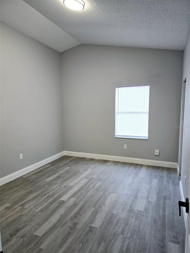 empty room with dark hardwood / wood-style flooring, vaulted ceiling, and a textured ceiling