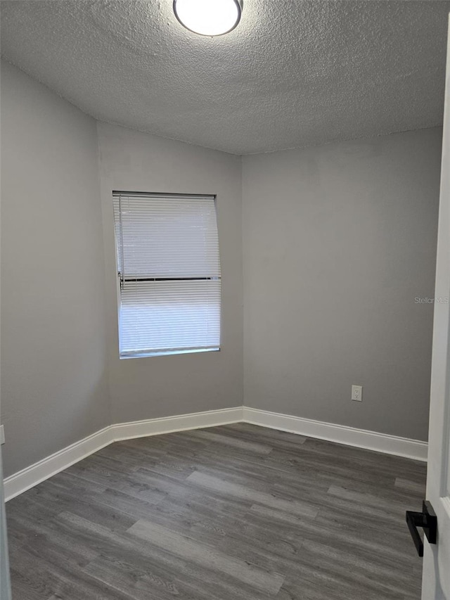 empty room featuring dark hardwood / wood-style flooring and a textured ceiling