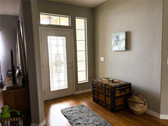 entryway featuring a textured wall, light wood finished floors, and baseboards