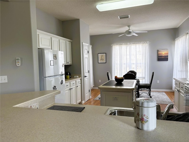 kitchen featuring white appliances, visible vents, light countertops, and a center island